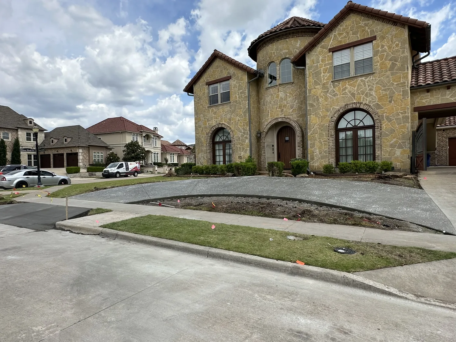 Wide finished residential concrete driveway and walkway at an upscale two-story home by Billy's Concrete