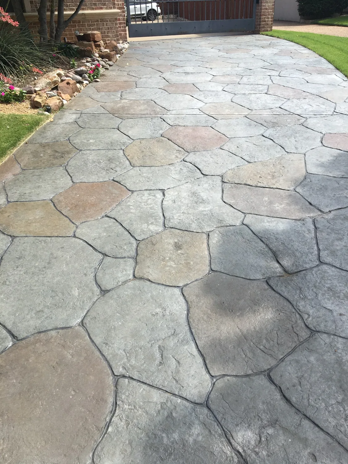 Stamped and hand-colored concrete driveway with a flagstone pattern and sealed finish by Billy's Concrete